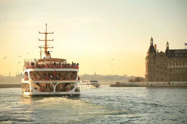 A commuter ferry nearing Kadıköy at sunset, Haydarpaşa Station behind