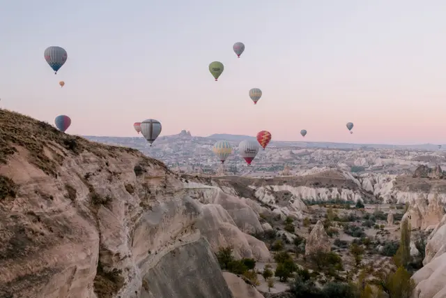 Gün doğumunda Kapadokya vadilerinin üzerinde süzülen balonlar