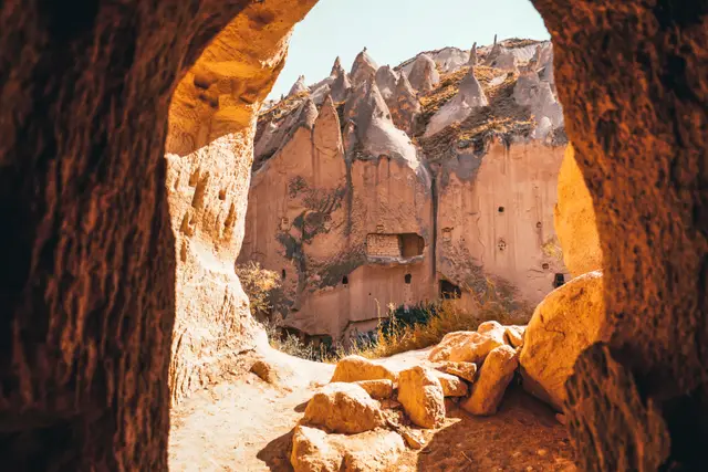 Kaya oyma yapılarla dolu bir vadiye bakan taş kemer